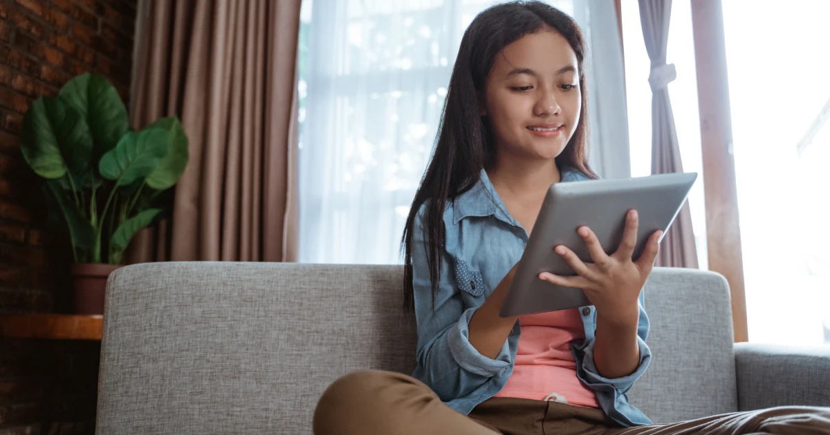 Young girl using tablet while sitting on couch