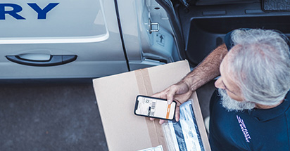 delivery driver using phone to scan package